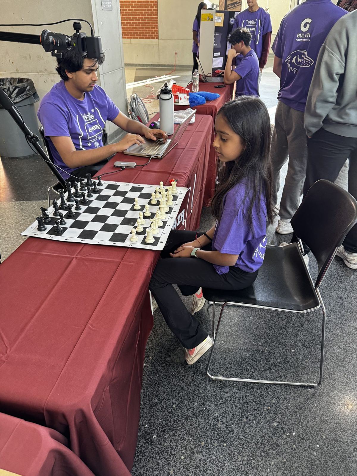A student plays chess against a robot arm