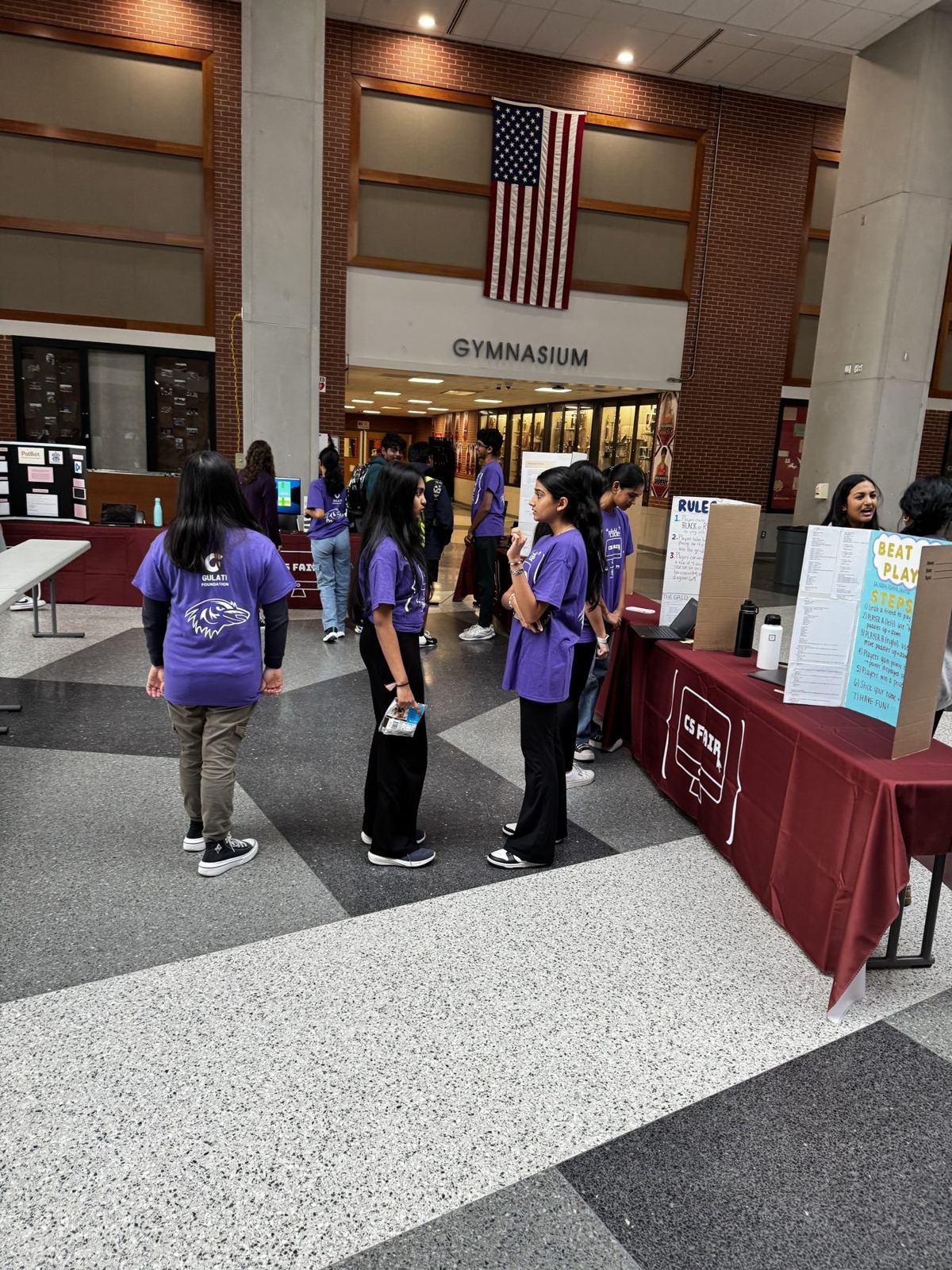 Students in purple CS Fair shirts at the project tables