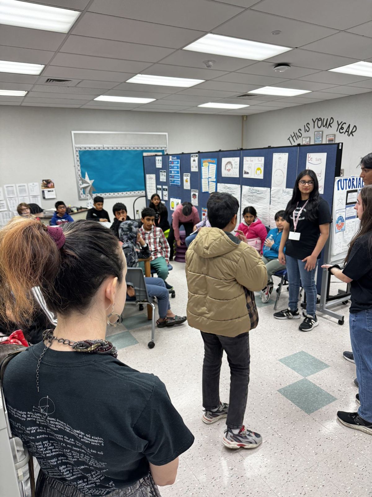 A high school volunteer leading younger students at a station